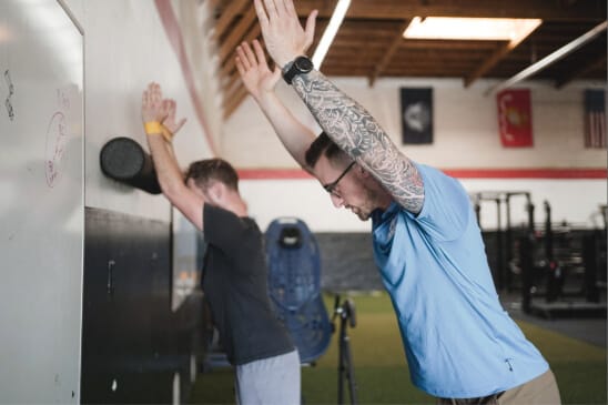 A phisiotherapy session showing two athletes with their arms outstretched.