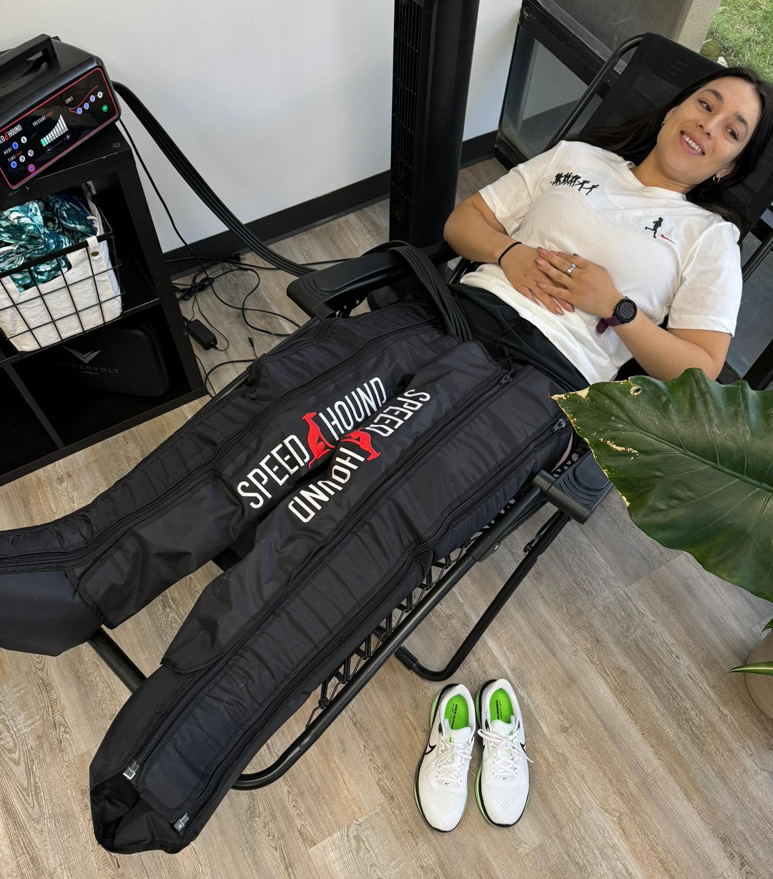 A person in a chair with their legs wrapped in a recovery device with the logo "Speed Houd"