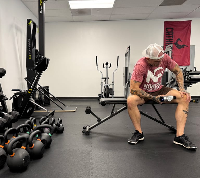 A person in a gym using a recovery device on their leg
